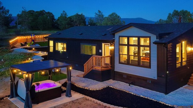 A modern two-story house with a covered outdoor seating area, a hot tub, and a well-maintained garden. - The Hills Edge - Stunning Views, Hot Tub & Games (Mariposa)