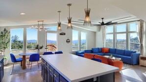 A spacious living area with a large sofa, a dining table, and a kitchen island. - The Hills Edge - Stunning Views, Hot Tub & Games (Mariposa)