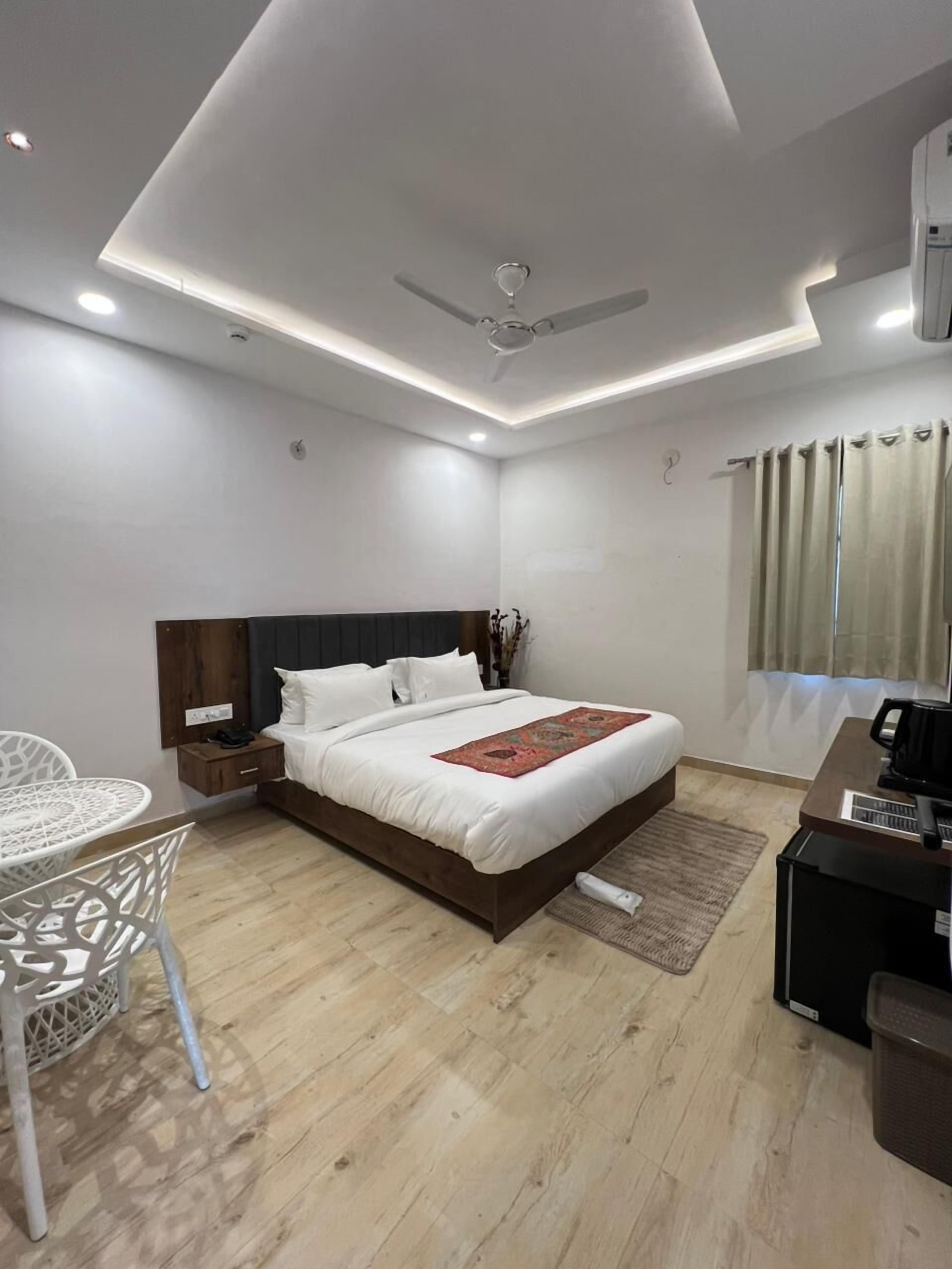 Une chambre d’hôtel moderne équipée d’un grand lit, d’un bureau, d’une chaise et d’un ventilateur de plafond.