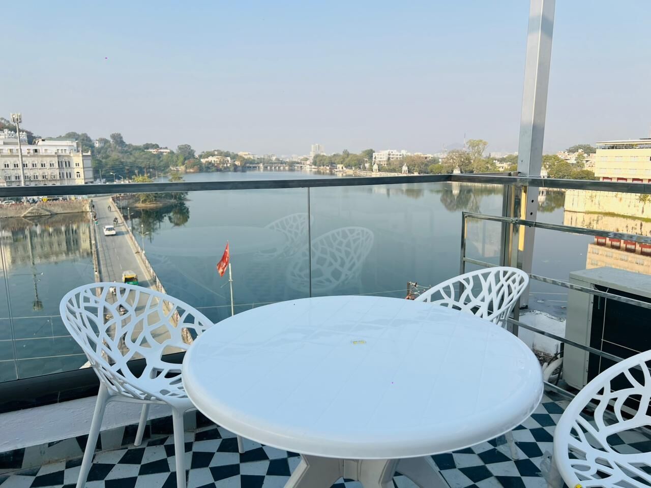 Un balcone con un tavolo rotondo e due sedie, con vista su un corpo d'acqua e edifici.