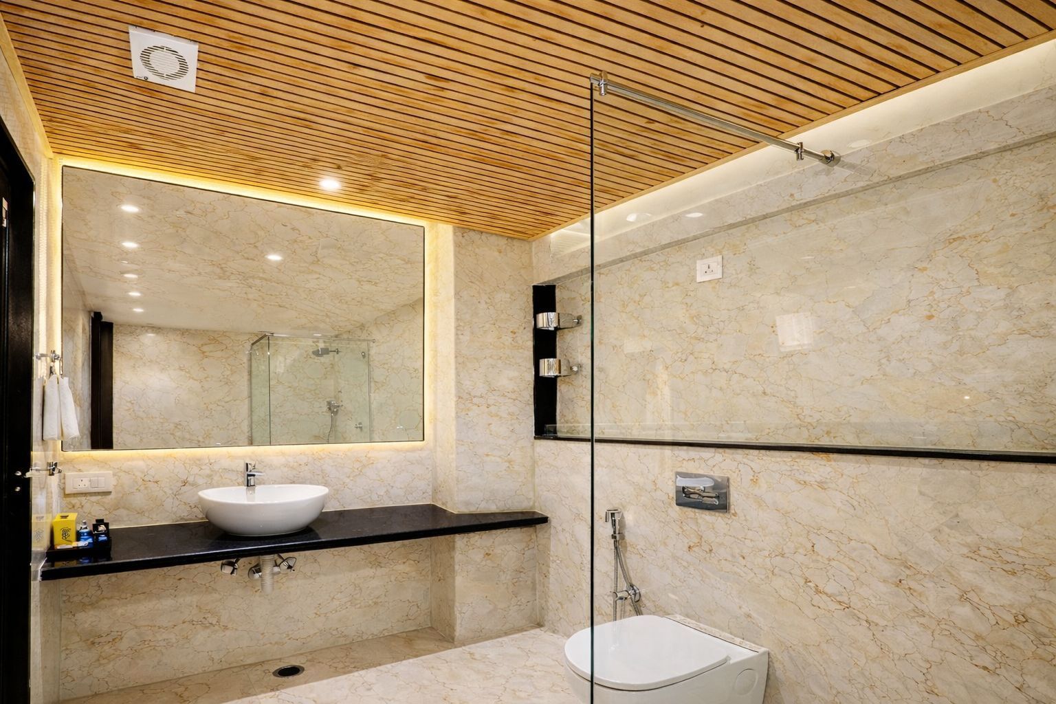 Un baño moderno con lavamanos de mármol, cabina de ducha de vidrio y techo de madera.