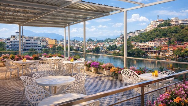 Terraza exterior con sillas y mesas blancas, con vistas a un río y un paisaje urbano.