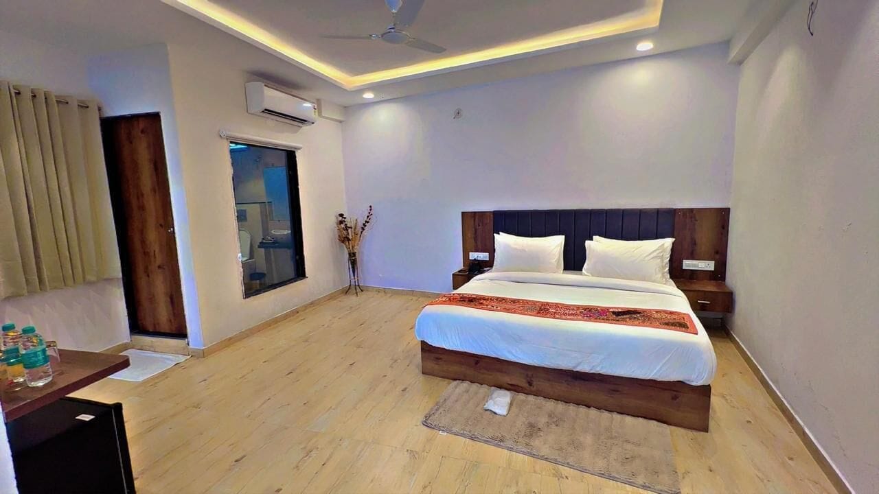 Una habitación de hotel con cama de madera, un escritorio con silla, una ventana con cortinas y un ventilador de techo.