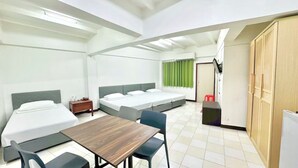 Een compacte hotelkamer met twee eenpersoonsbedden, een tafeltje en een stoel.