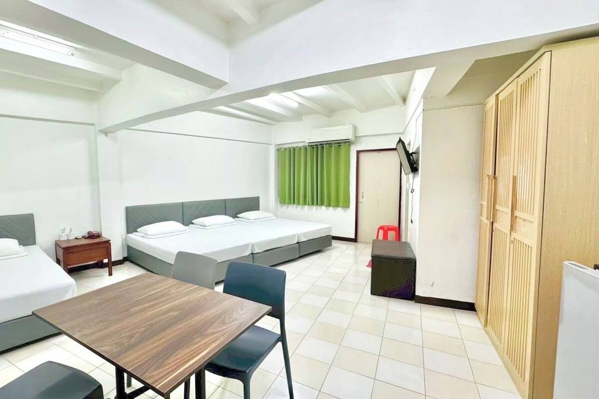 Ein kompaktes Hotelzimmer mit zwei Einzelbetten, einem kleinen Tisch und einem Stuhl.