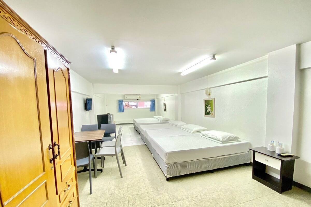 Ein Hotelzimmer mit einem Bett, einem Schreibtisch, einem Stuhl, einem Kleiderschrank und einem kleinen Tisch mit Toilettenartikeln.