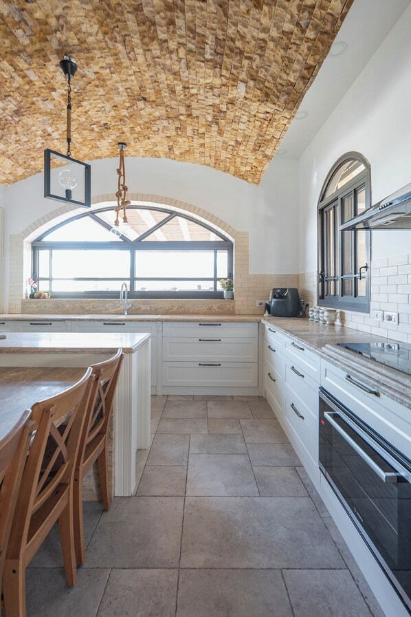 Una cocina con techo de piedra, un ventanal grande y una estufa moderna.
