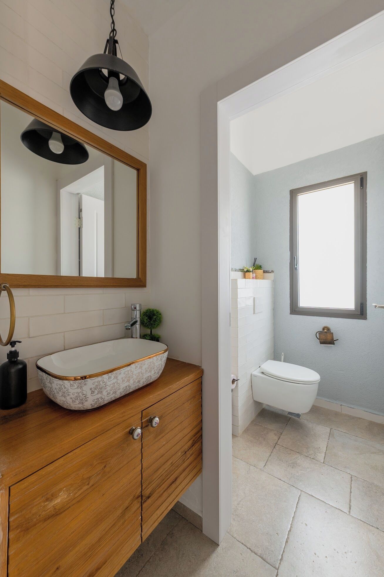Een moderne badkamer met een houten wastafelmeubel, een grote spiegel en een losstaand toilet.