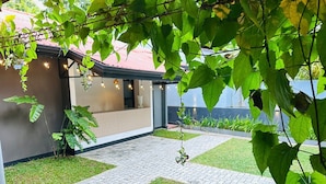 Ein modernes Haus mit gepflasterter Terrasse, einem kleinen Garten und Lichterketten.
