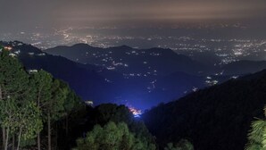 A nighttime view of a mountainous area with a valley and a city in the distance. - The Pine Paradise (Kasauli)