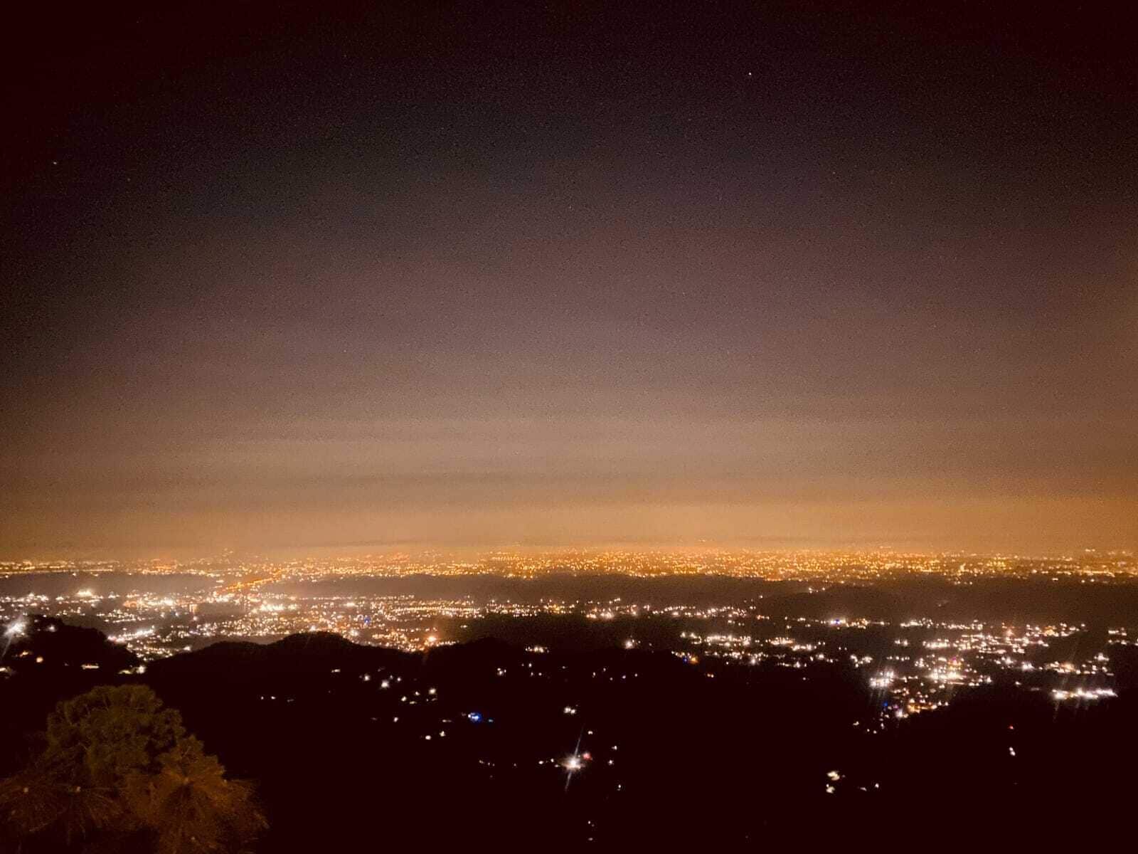 A nighttime cityscape with a view of the city lights from a high vantage point.