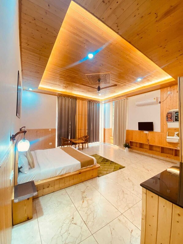 A modern hotel room with a wooden ceiling, a bed, a desk, a TV, and a bathroom.