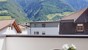 Un edificio residencial con techo inclinado, un balcón y vistas a un paisaje montañoso.
