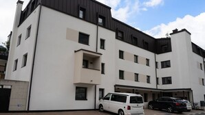 Un edificio residencial moderno de varios pisos con fachada blanca y techo oscuro.