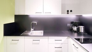 Una cocina moderna con armarios blancos, encimera negra, pileta de acero inoxidable y cafetera.