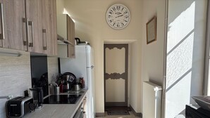 A modern kitchen with wooden cabinets, a built-in oven, a coffee maker, and a kettle. - Gite in manor near futuroscope (Saint-Martin-la-Pallu)