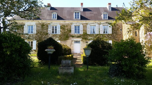 A historic building with a symmetrical facade, multiple windows with shutters, and a central entrance with steps leading to a door. - Gite in manor near futuroscope (Saint-Martin-la-Pallu)