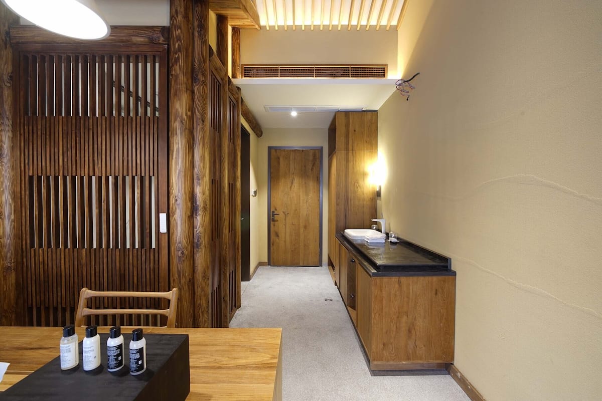 A hotel room with a wooden partition, a sink, and a chair.