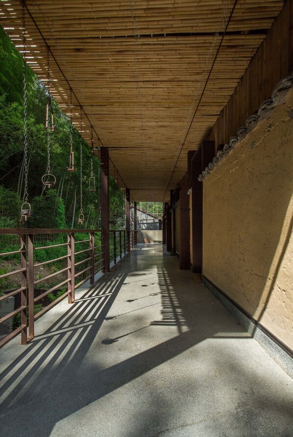 A covered walkway with a wooden ceiling, metal railings, and a concrete floor.