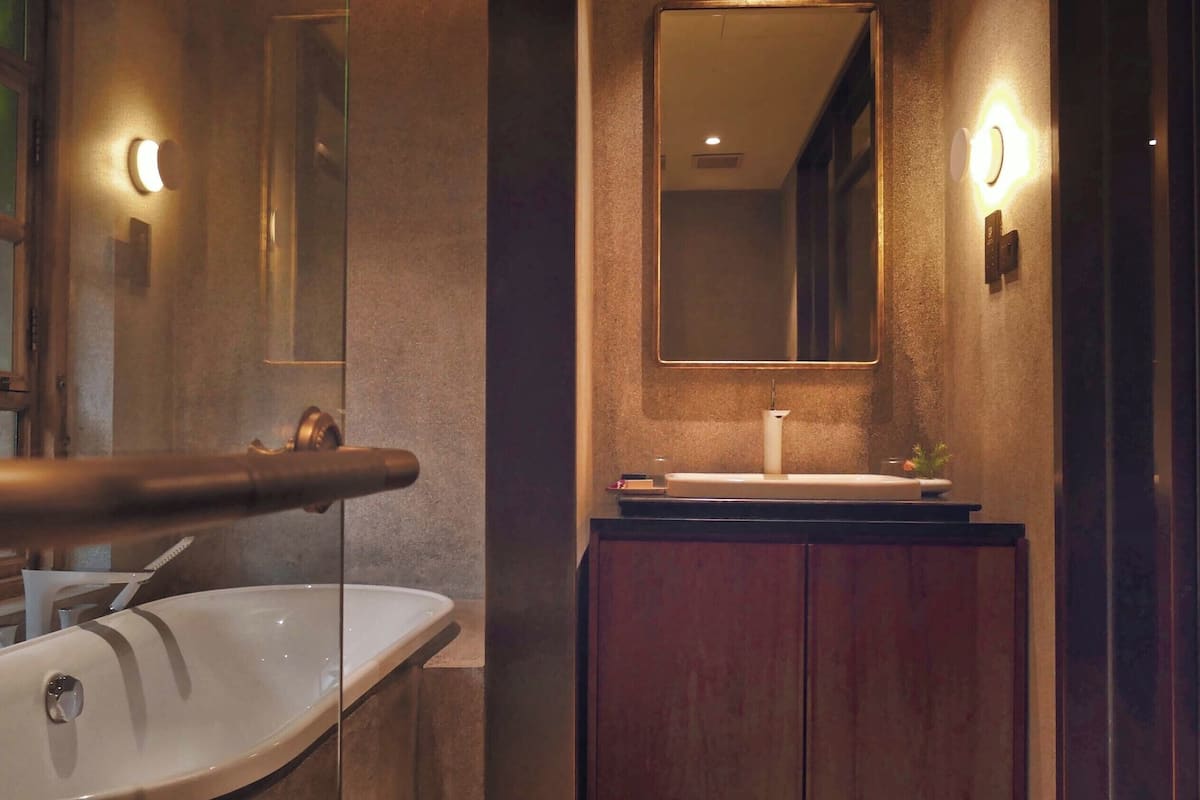 A bathroom with a freestanding bathtub, a vanity with a mirror, and a wooden cabinet.
