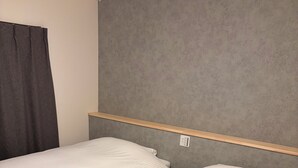 A bedroom with two beds, a grey headboard, and a wooden shelf above the beds. - HOTEL LUNA STELLA (Sendai)