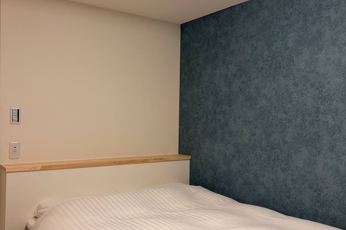 A bedroom with a bed, a wooden headboard, a blue accent wall, and a ceiling light.