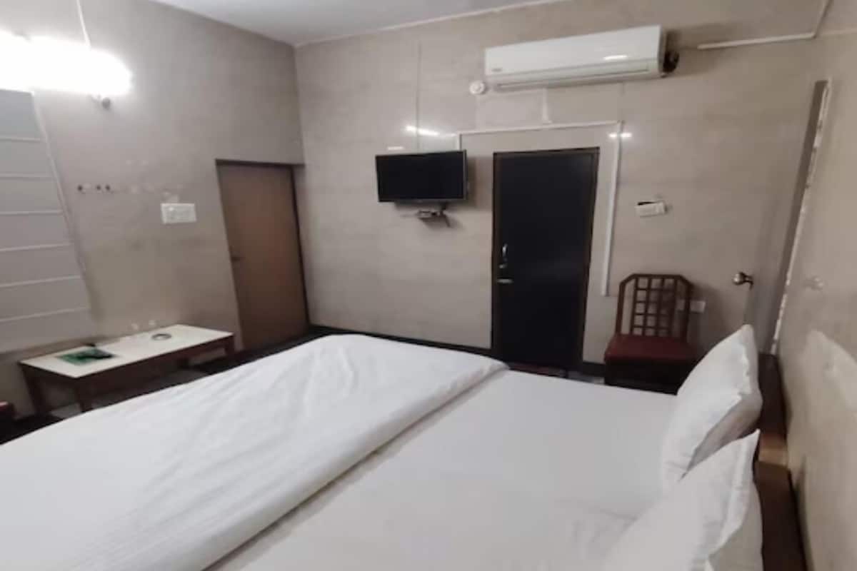 Une chambre d’hôtel équipée d’un lit, d’un bureau, d’une chaise, d’une télévision et d’un appareil de climatisation.