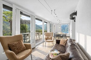 Un amplio espacio de sala con un gran ventanal, un sofá, una silla y una mesa de comedor.
