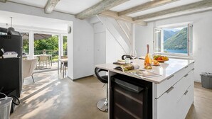 Eine moderne Küche mit einer großen Kochinsel, einem Essbereich mit Stühlen und Bergblick durch ein Fenster.