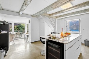 Una cocina moderna con una isla grande, un comedor con sillas y vistas al exterior.