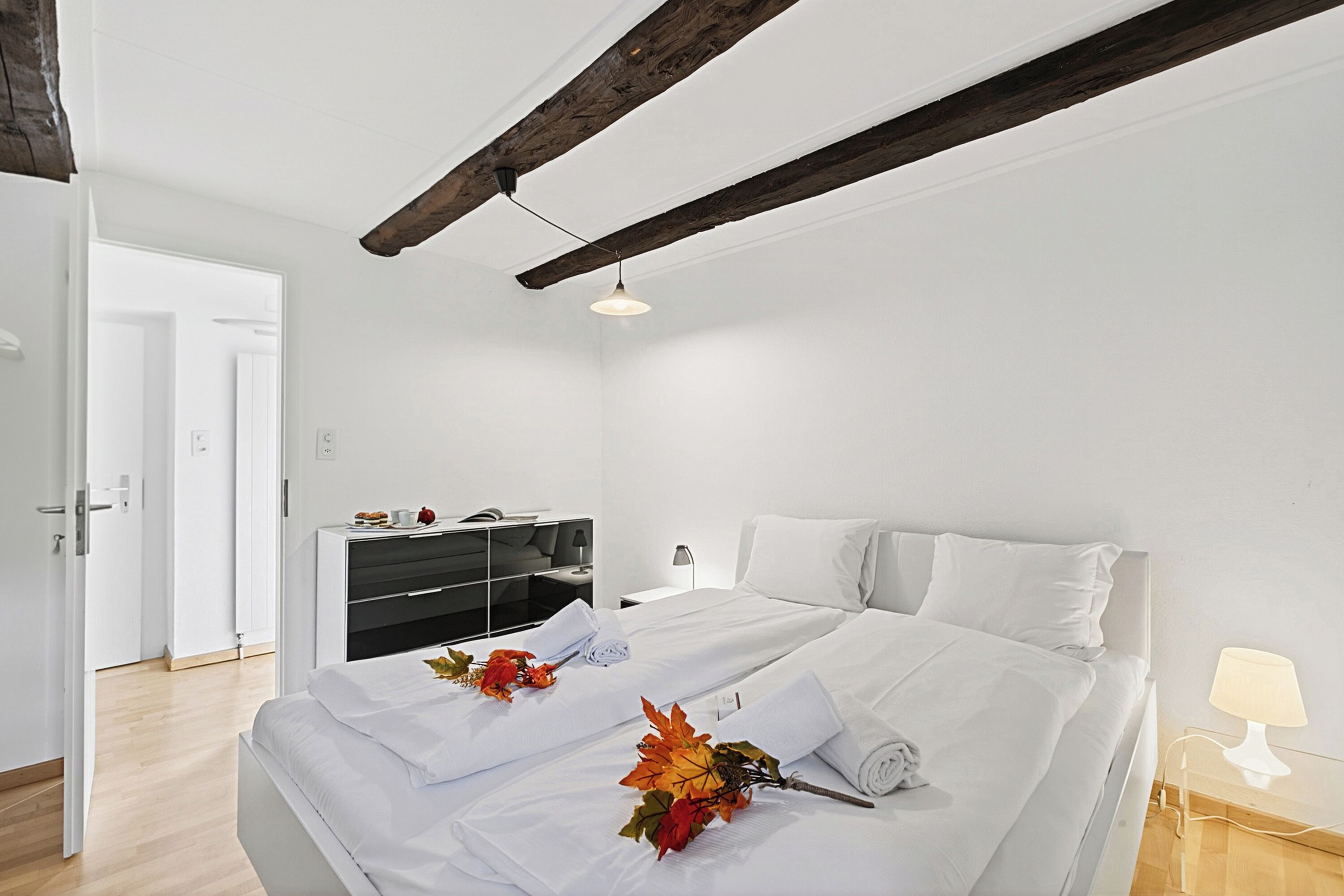 A modern hotel room with a large bed, a desk, and a wardrobe.