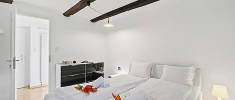 A modern hotel room with a large bed, a desk, and a wardrobe.