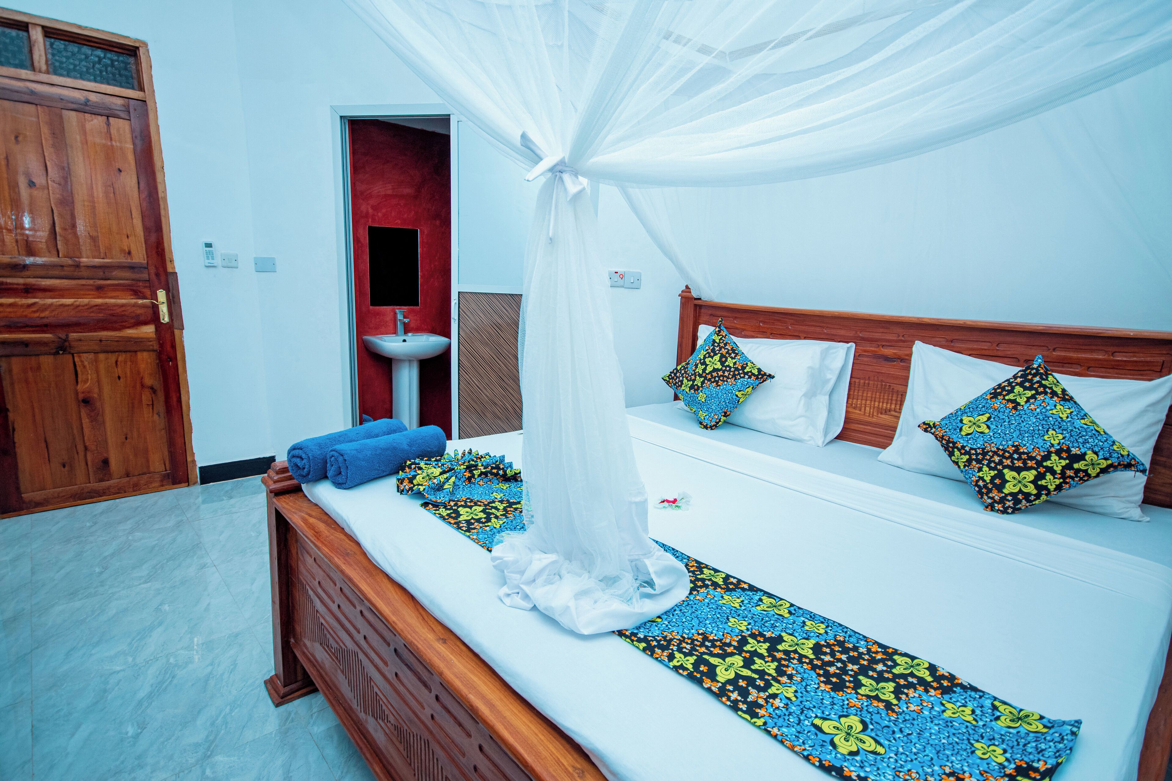 Un dormitorio con cama de madera, ropa de cama blanca y dosel.