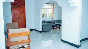 Ein Zimmer mit einer Holzbank, einem grauen Sofa und einer Treppe zu einer erhöhten Ebene.