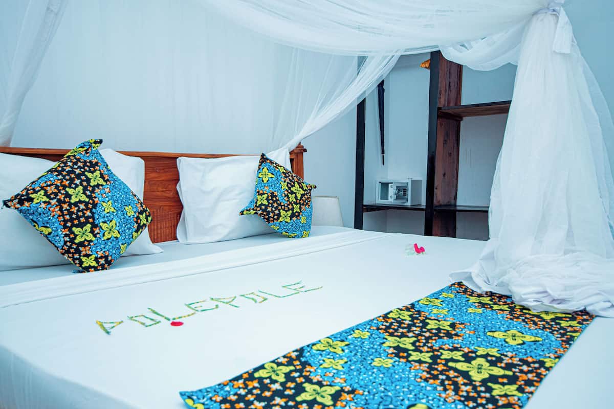 A hotel room with a bed, white curtains, and a canopy.
