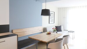 A modern, well-lit room with a wooden dining table, white chairs, a bench, and a black pendant light. - Apartment Luis 2 - Alpstay (Naturns)