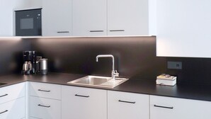 A modern kitchen with a stainless steel sink, white cabinets, and a built-in oven. - Apartment Luis 2 - Alpstay (Naturns)