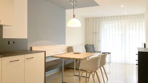 A modern kitchen with a wooden table, two chairs, and a bench. - Apartment Luis 2 - Alpstay (Naturns)