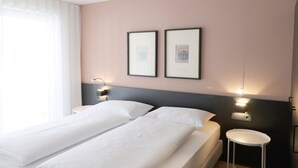 A double bed with white linens, two bedside tables, wall-mounted lights, and framed pictures on the wall. - Apartment Luis 2 - Alpstay (Naturns)