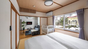 Habitación de hotel con una cama grande, una cuna, un televisor y vistas al exterior.