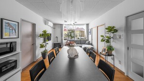 Un comedor moderno con una mesa larga, sillas negras y plantas en macetas.