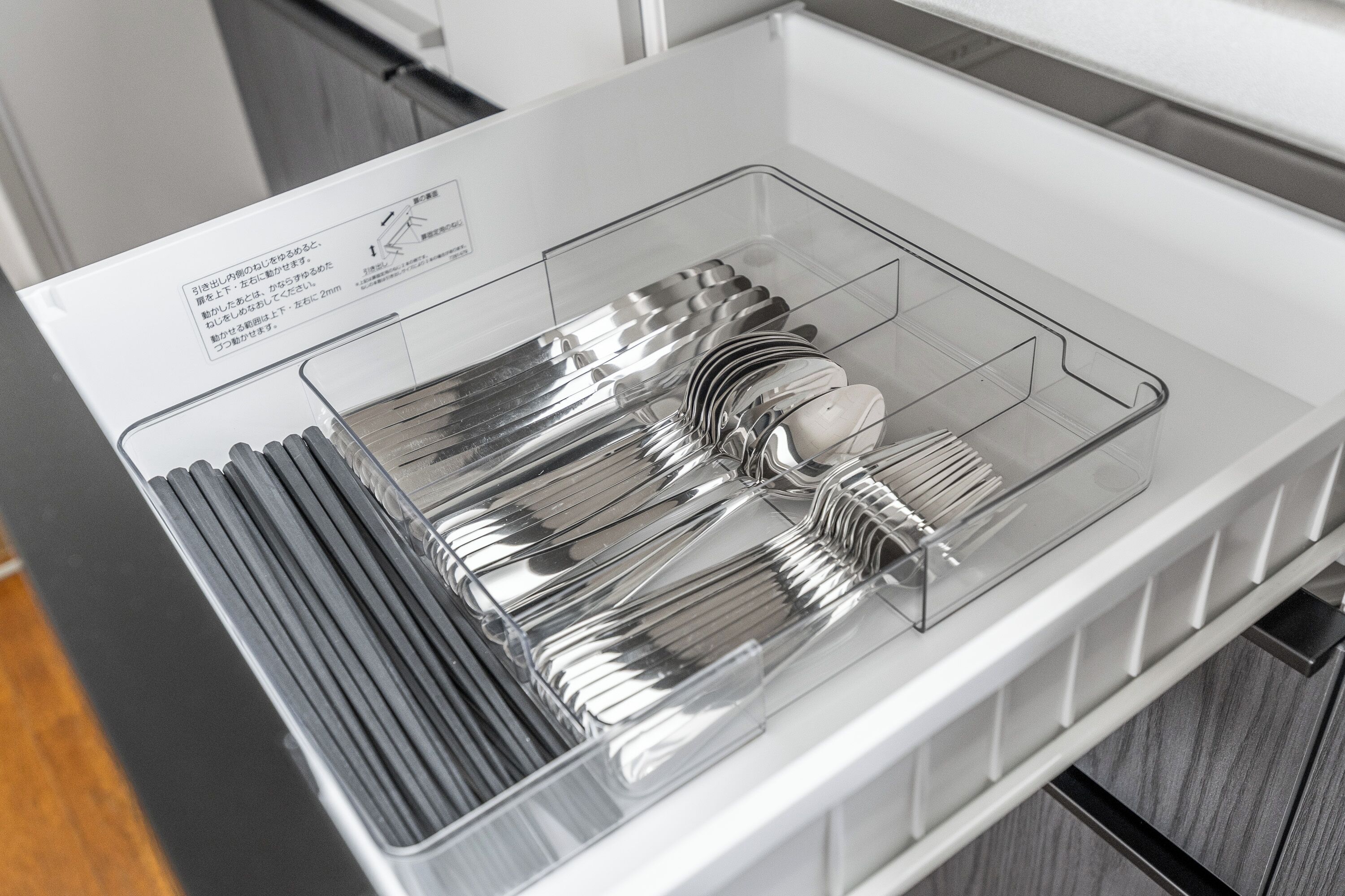 A kitchen drawer with a clear organizer containing various utensils.