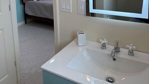 A bathroom with a white sink, a mirror, and a towel rack. - Flamingo Inn - 2 Queen with Kitchenette #204 (Fort Myers Beach)