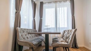 Un comedor con una mesa y dos sillas acolchadas, cortinas y una ventana con vistas.