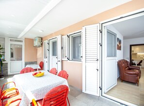 A dining area with a table and chairs, a kitchen in the background, and a living area with a sofa. - Guest House 4M Gregović (Petrovac)