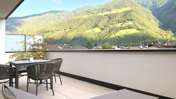 A balcony with a table and chairs, overlooking a mountainous landscape. - Apartment Luis 3 - Alpstay (Naturns)
