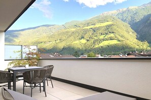 A balcony with a table and chairs, overlooking a mountainous landscape. - Apartment Luis 3 - Alpstay (Naturns)