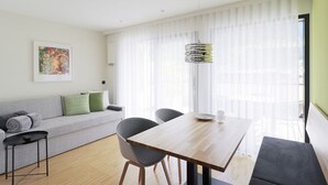 A modern living room with a wooden dining table, grey sofa, and a black coffee table. - Apartment Luis 3 - Alpstay (Naturns)