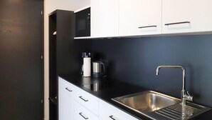 A modern kitchen with a black countertop, stainless steel sink, and white cabinets. - Apartment Luis 3 - Alpstay (Naturns)