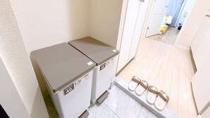 Une buanderie équipée de deux machines à laver et d’une paire de chaussons posée sur une étagère.